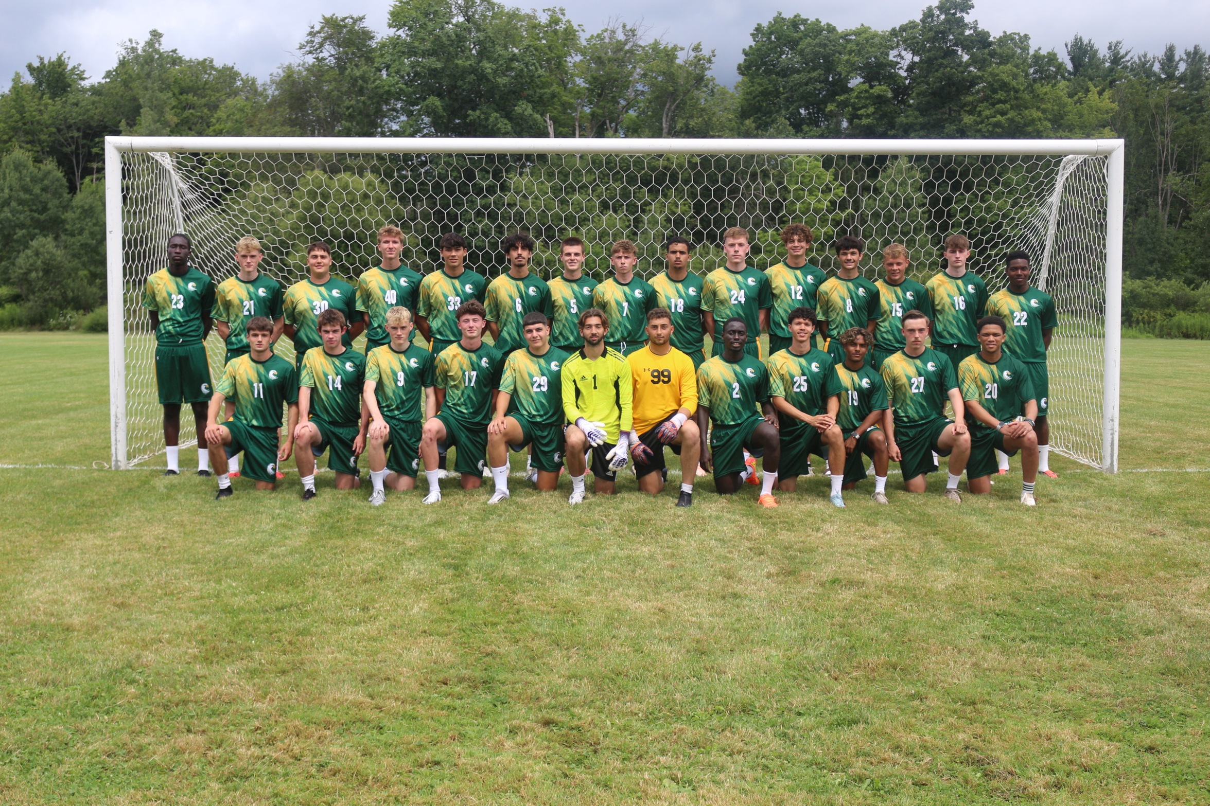 JCC men's soccer team posing as a group inside the goal of their home field.